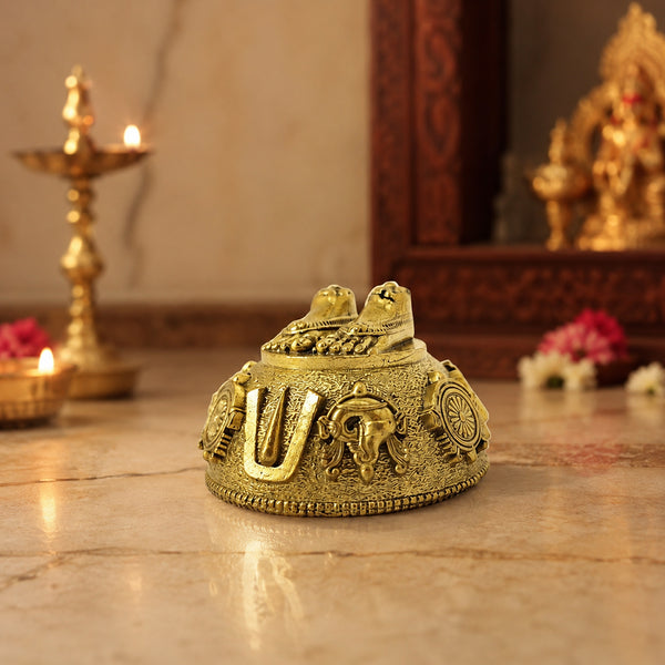 Brass Perumal Patham idol in temple-style pooja room setting with candles