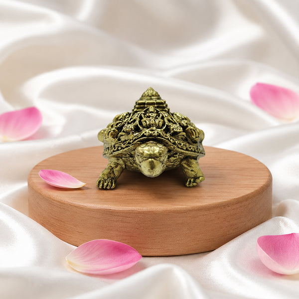 Antique brass Ashtalakshmi tortoise (Kachua) placed on a wooden pedestal with rose petals for Vastu decor.