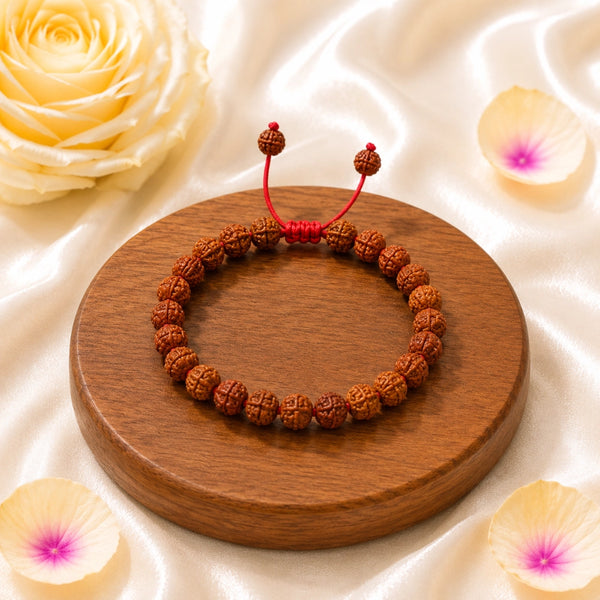 Premium authentic Rudraksha bead bracelet displayed on a wooden base with rose petals, perfect for daily spiritual protection