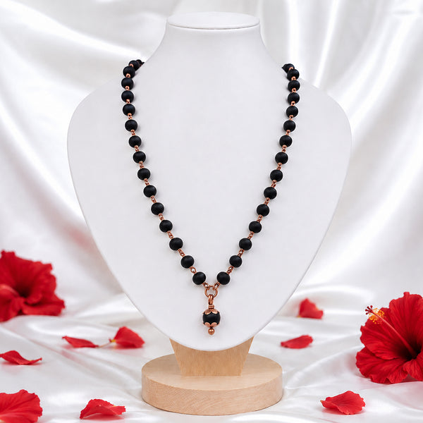Black bead Mangalsutra necklace with copper-toned pendant displayed on a white jewelry bust