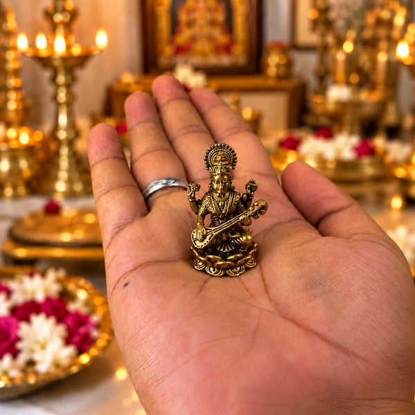 Small brass Saraswati idol held on an open palm to show its size