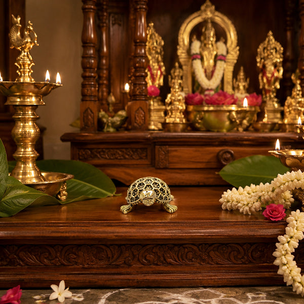 Brass Vastu Tortoise placed on a sacred puja altar with lamps and flower garlands for prosperity.