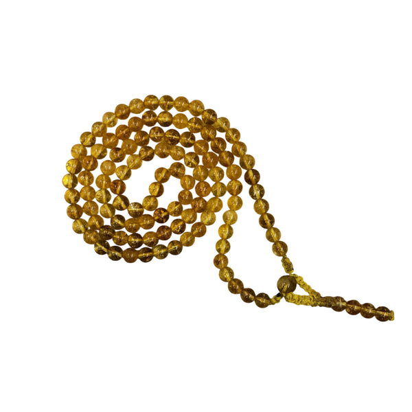 A traditional Citrine crystal prayer mala coiled in a spiral, showing the clarity and golden-yellow hue of the polished crystal beads.