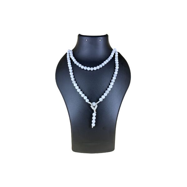 A white Howlite crystal mala necklace with natural grey veining, worn doubled over a black jewelry mannequin bust for a striking contrast.