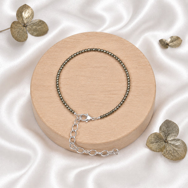 High-quality faceted Pyrite beads on a spiritual chain bracelet displayed elegantly on white silk for a premium aesthetic.