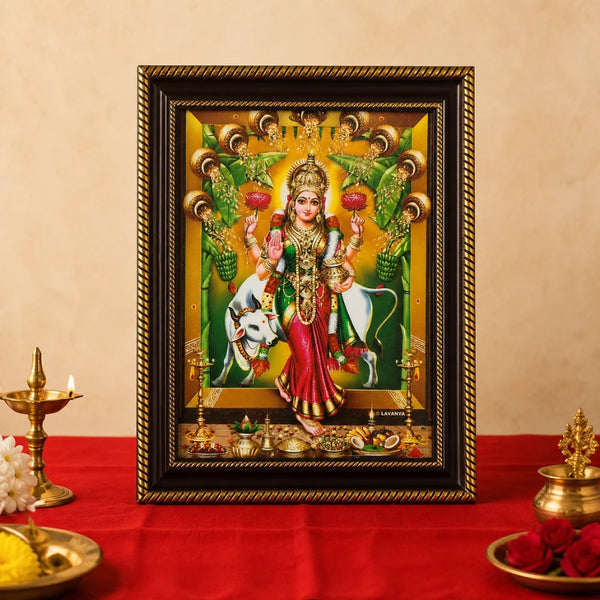 Traditional Goddess Lakshmi photo frame placed on a red cloth pooja altar with brass oil lamps and flowers, demonstrating home temple decoration ideas.