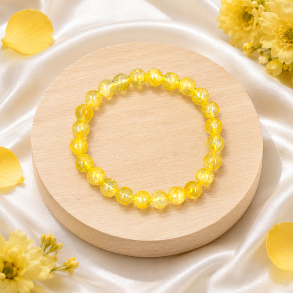 Side view of a handcrafted 8mm yellow citrine bead bracelet displayed with elegant yellow blossoms.