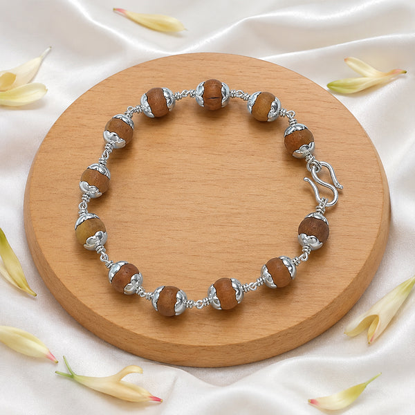 Handcrafted Chandanam Sandalwood healing bracelet displayed with white jasmine flowers for a pure spiritual aesthetic.