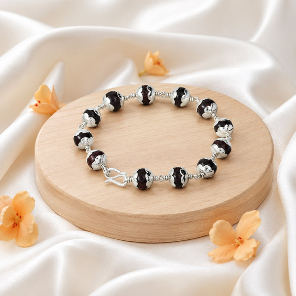 Handcrafted Red Sandalwood healing bracelet displayed with delicate blossoms on silk for a luxury spiritual aesthetic.