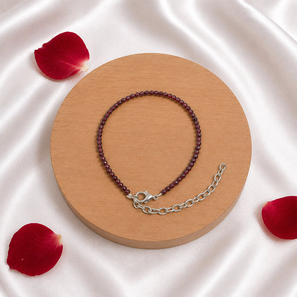 High-quality faceted Red Garnet beads on a spiritual chain bracelet displayed elegantly with red rose petals for a luxury aesthetic.