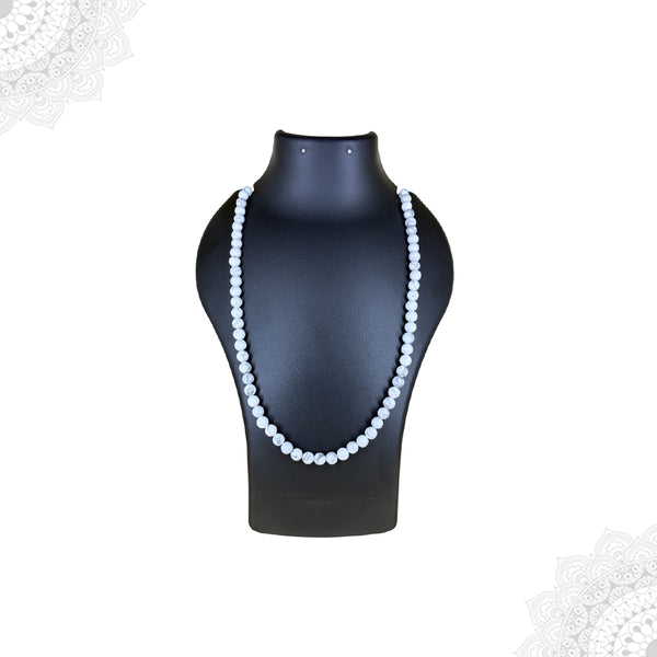 A long strand of polished white Howlite beads displayed as a mala necklace on a black jewelry bust, highlighting its marble-like appearance.