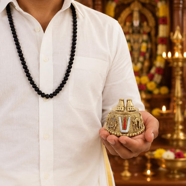 Man wearing a karungali mala with a Perumal Patham pendant, holding the pendant in hand