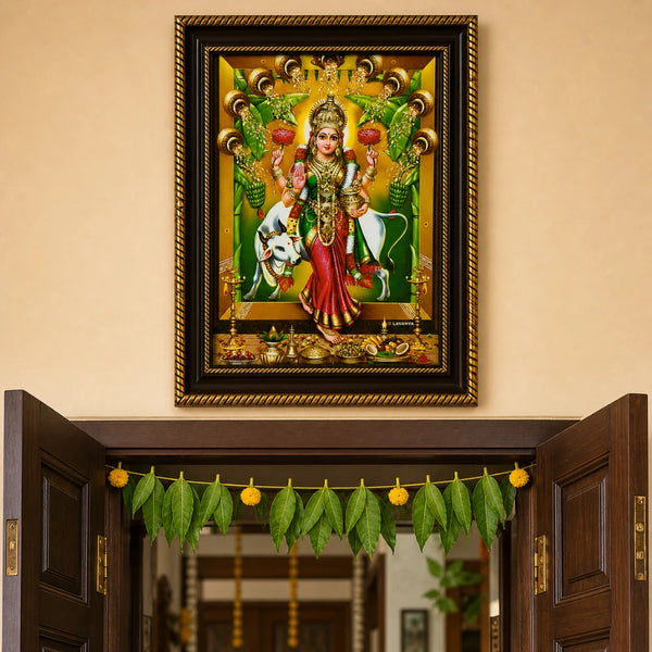Goddess Lakshmi photo frame mounted above a traditional Indian wooden doorway decorated with mango leaves, showing Vastu-compliant placement for home prosperity