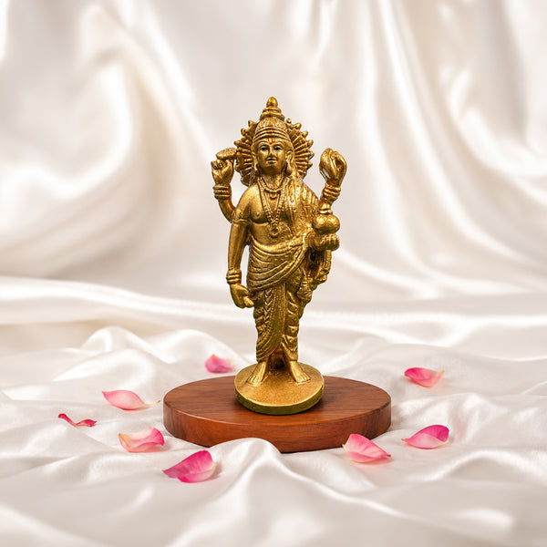 4.9-inch Lord Dhanvantri statue in gold finish on a wooden base with rose petals.