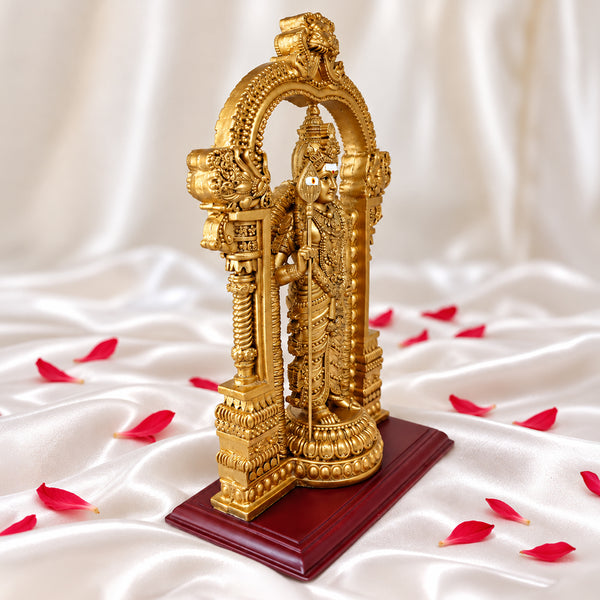 Right side view of gold Murugan statue holding the vel under the temple arch