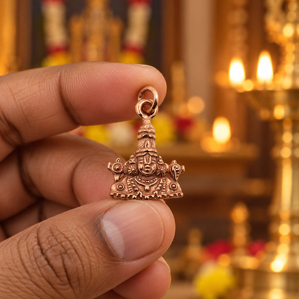 Rose gold Perumal pendant shaped like the Tirumala gopuram, held in hand