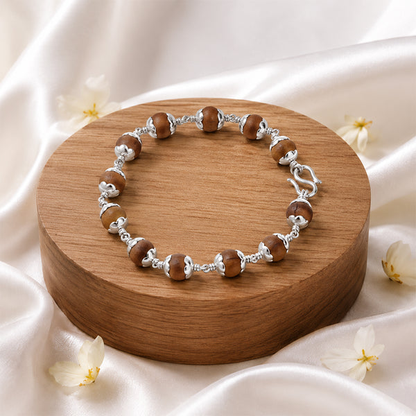 Premium Sandalwood (Chandanam) bracelet featuring silver-toned capped beads and a traditional secure S-hook clasp on a luxury wooden display.