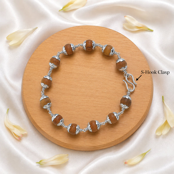 Detailed view of the traditional secure S-hook metal clasp on a silver-capped Sandalwood bead bracelet.