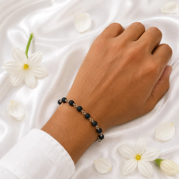 A person wearing the artisanal silver wire-wrapped Karungali wood bracelet, showcasing its elegant and adjustable fit.