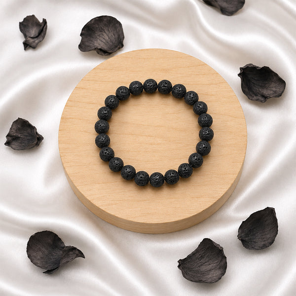 Handcrafted Lava Rock stretch bracelet displayed with dark petals for a premium, earth-element spiritual aesthetic.
