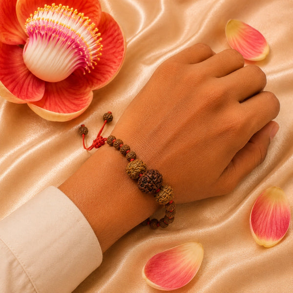 A person wearing the 3 Mukhi and 5 Mukhi Rudraksha energy bracelet on a red adjustable cord.